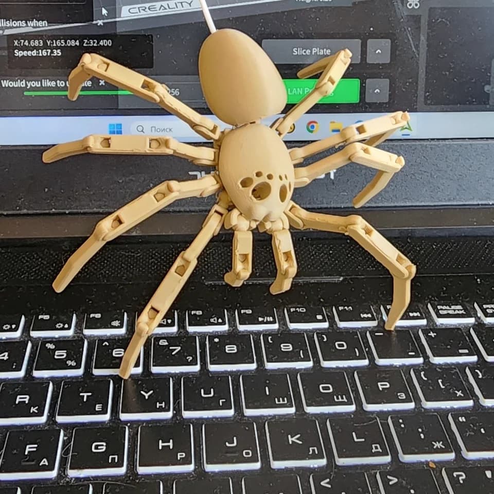 A pale facehugger figurine with segmented limbs on a laptop, showing a close view of the body and connections.