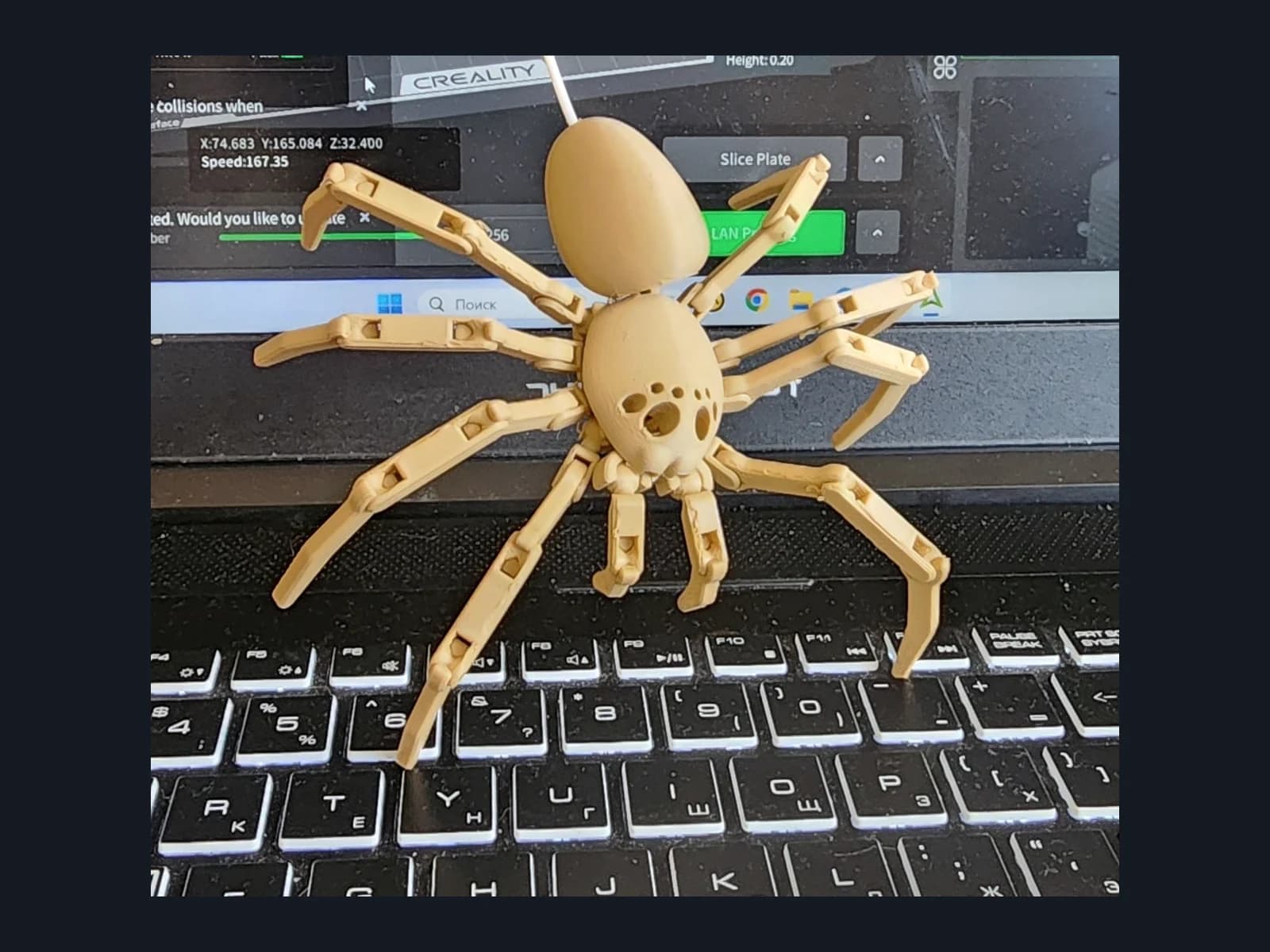A pale facehugger figurine with segmented limbs on a laptop, showing a close view of the body and connections.