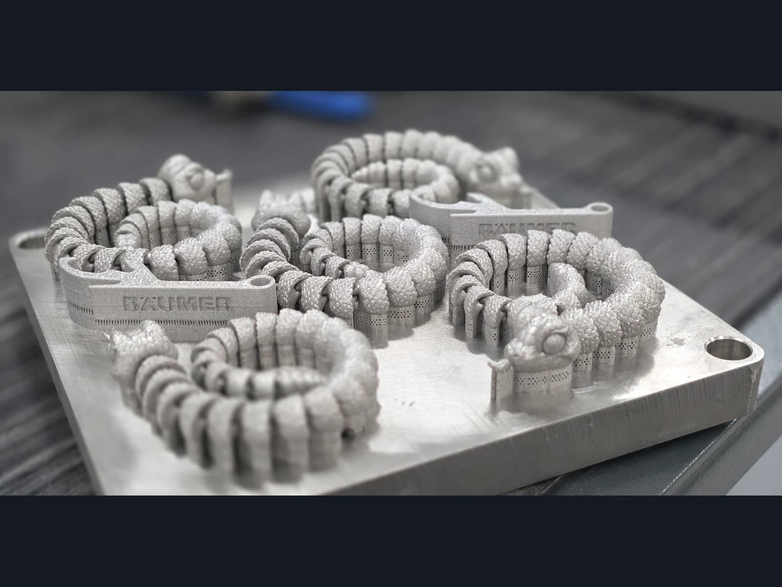 Five silver-coloured dragons with coiled bodies on a shared build plate with supports.