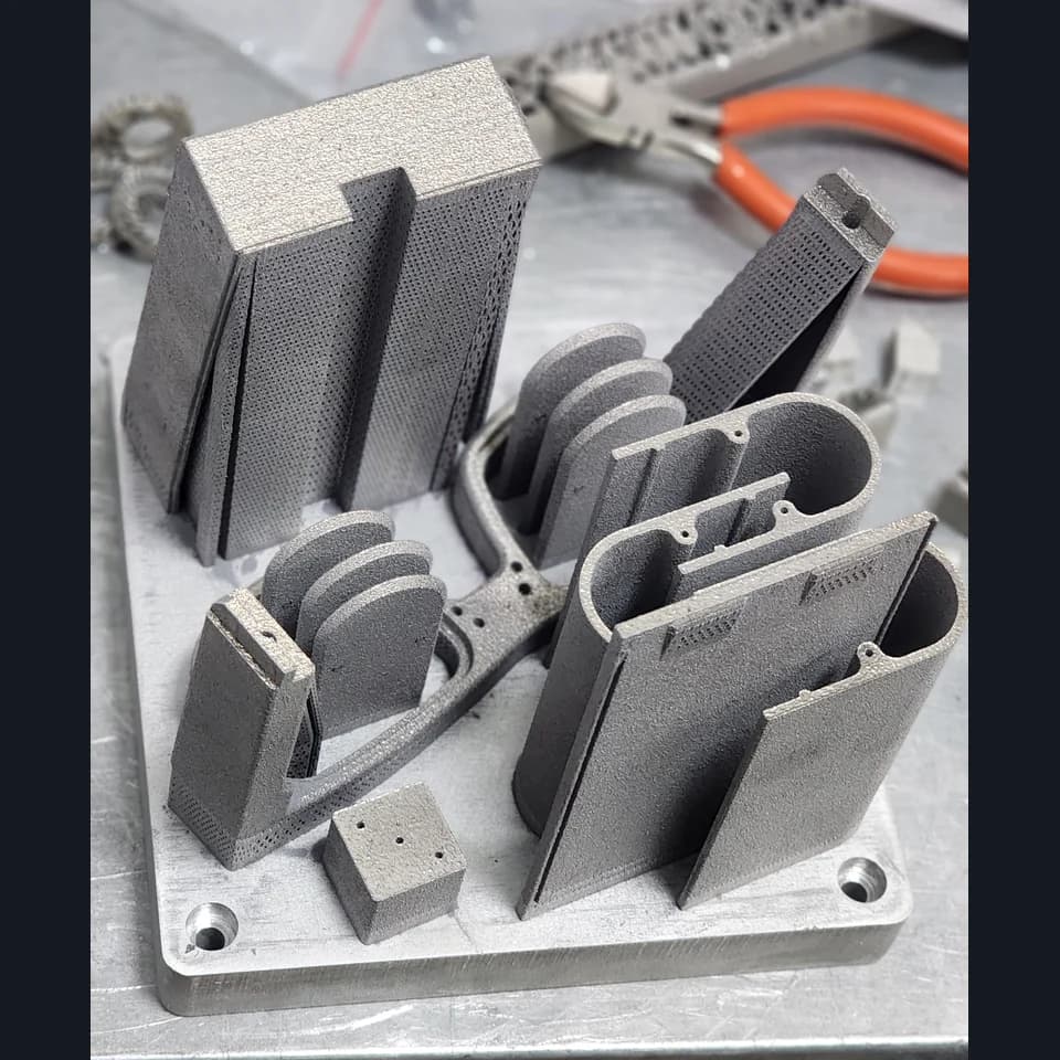 Grey housing elements and brackets with holes and supports on a shared build plate.