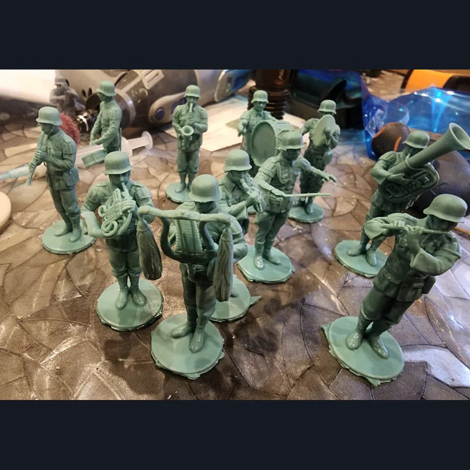 Green miniatures of helmeted musicians with wind instruments and a drum on individual bases.