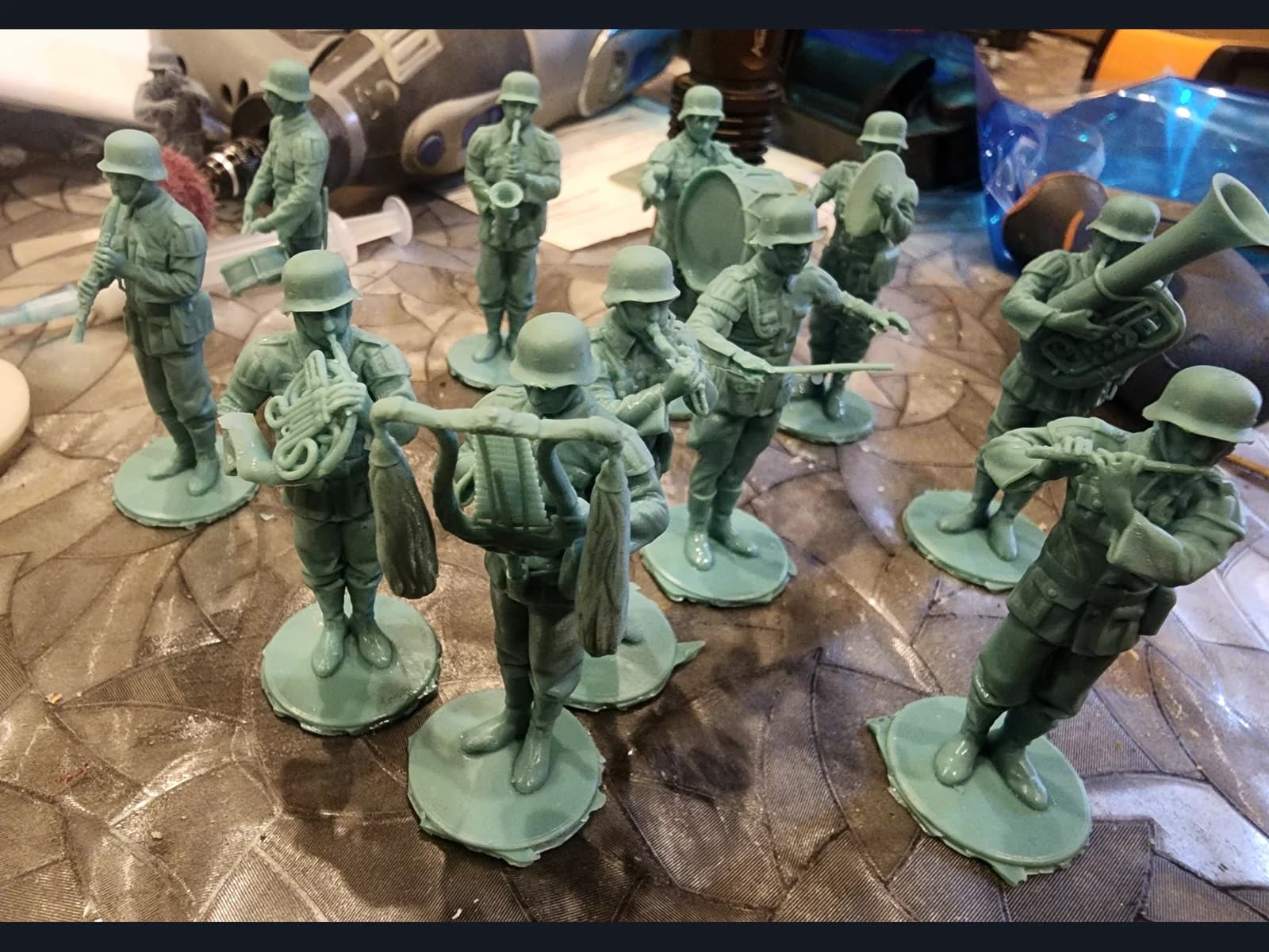 Green miniatures of helmeted musicians with wind instruments and a drum on individual bases.