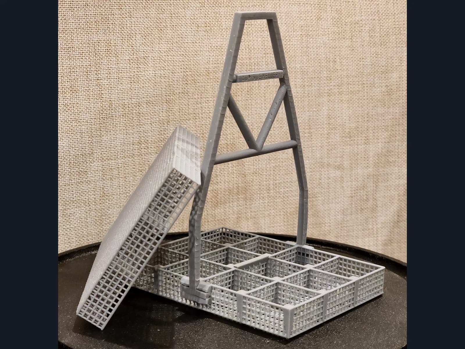 A grey mesh basket with dividers and a tall handle, with a separate mesh section standing beside it.