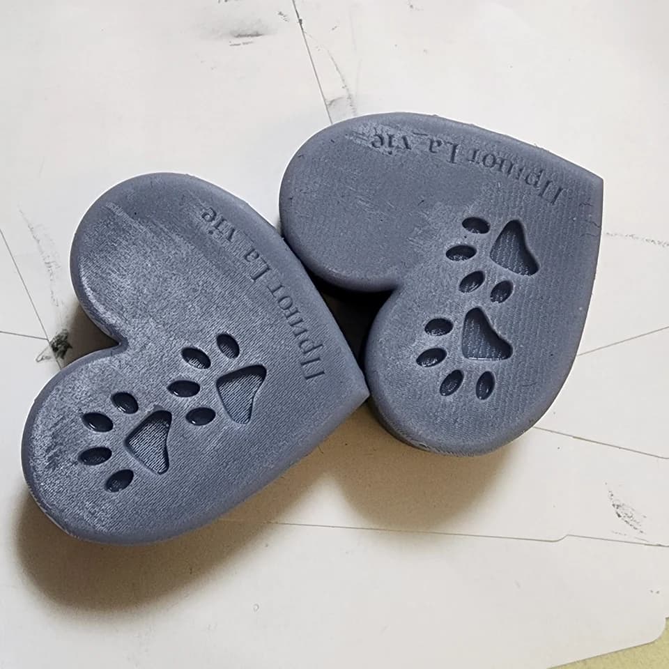 Two grey hearts with recessed paw prints and a La Vie shelter inscription on pale paper.