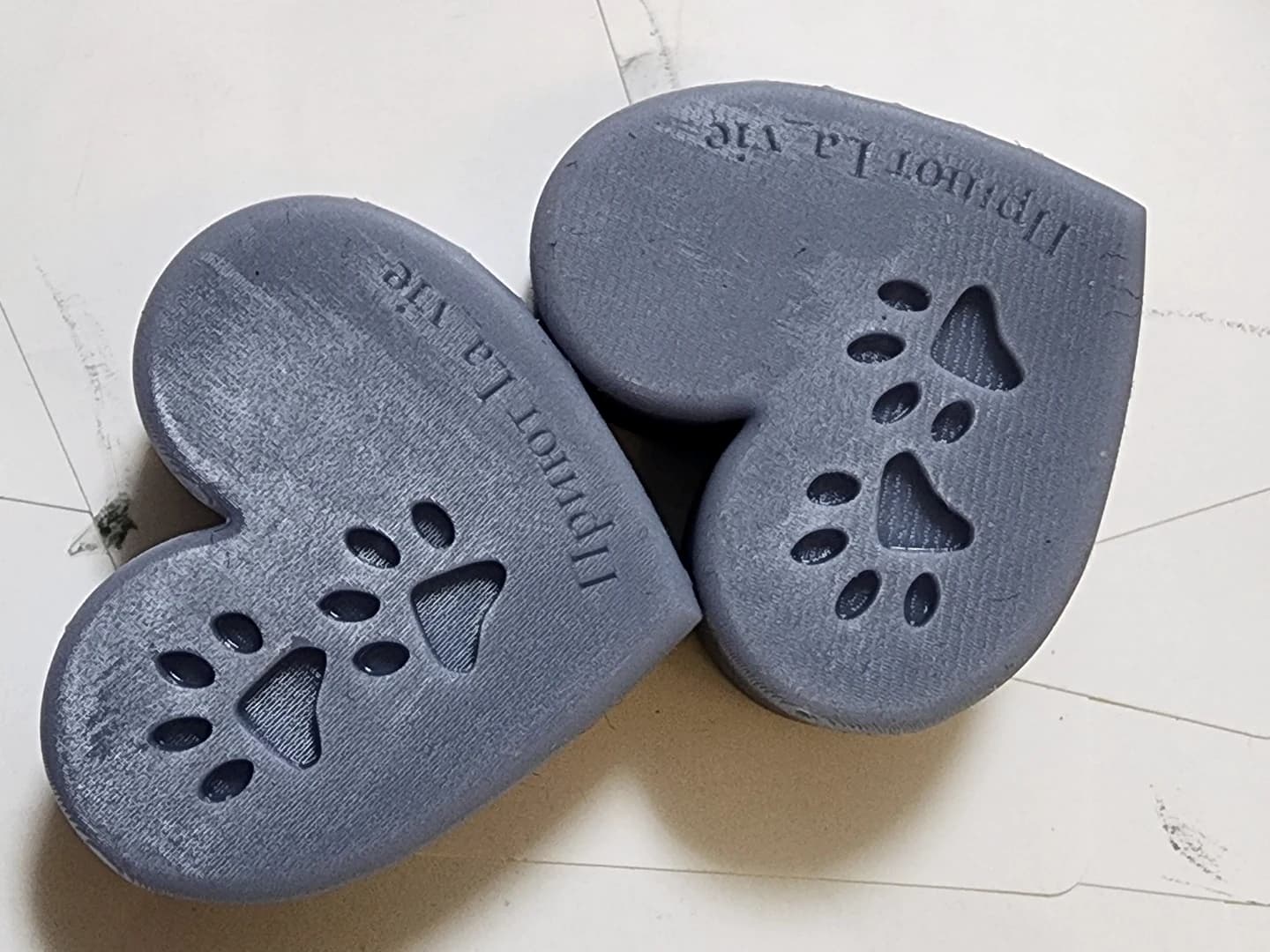 Two grey hearts with recessed paw prints and a La Vie shelter inscription on pale paper.