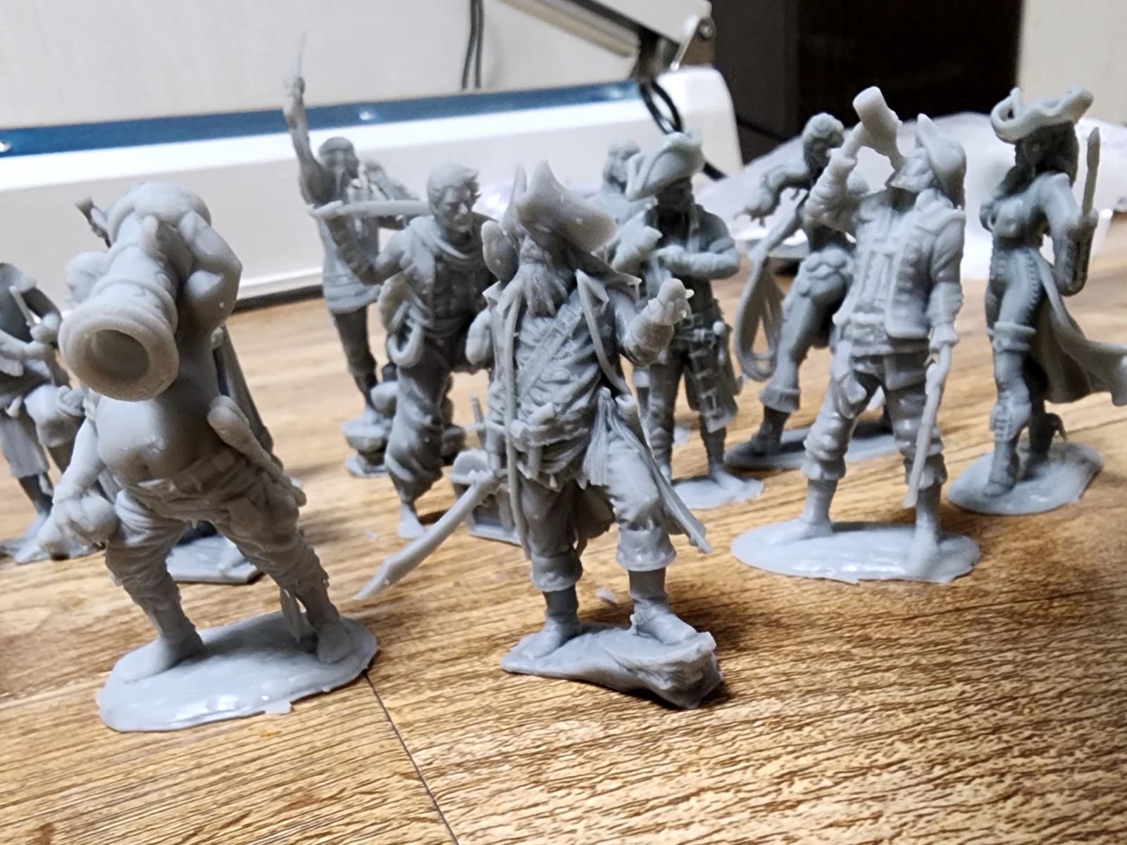 Grey pirate miniatures on individual bases, including figures in tricorn hats, with sabres and a cannon carried on a shoulder.
