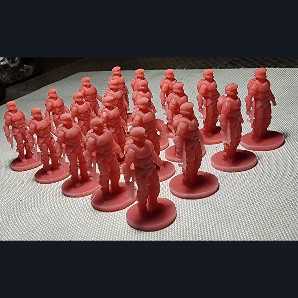 Rows of red soldier miniatures with helmets and equipment on round bases.