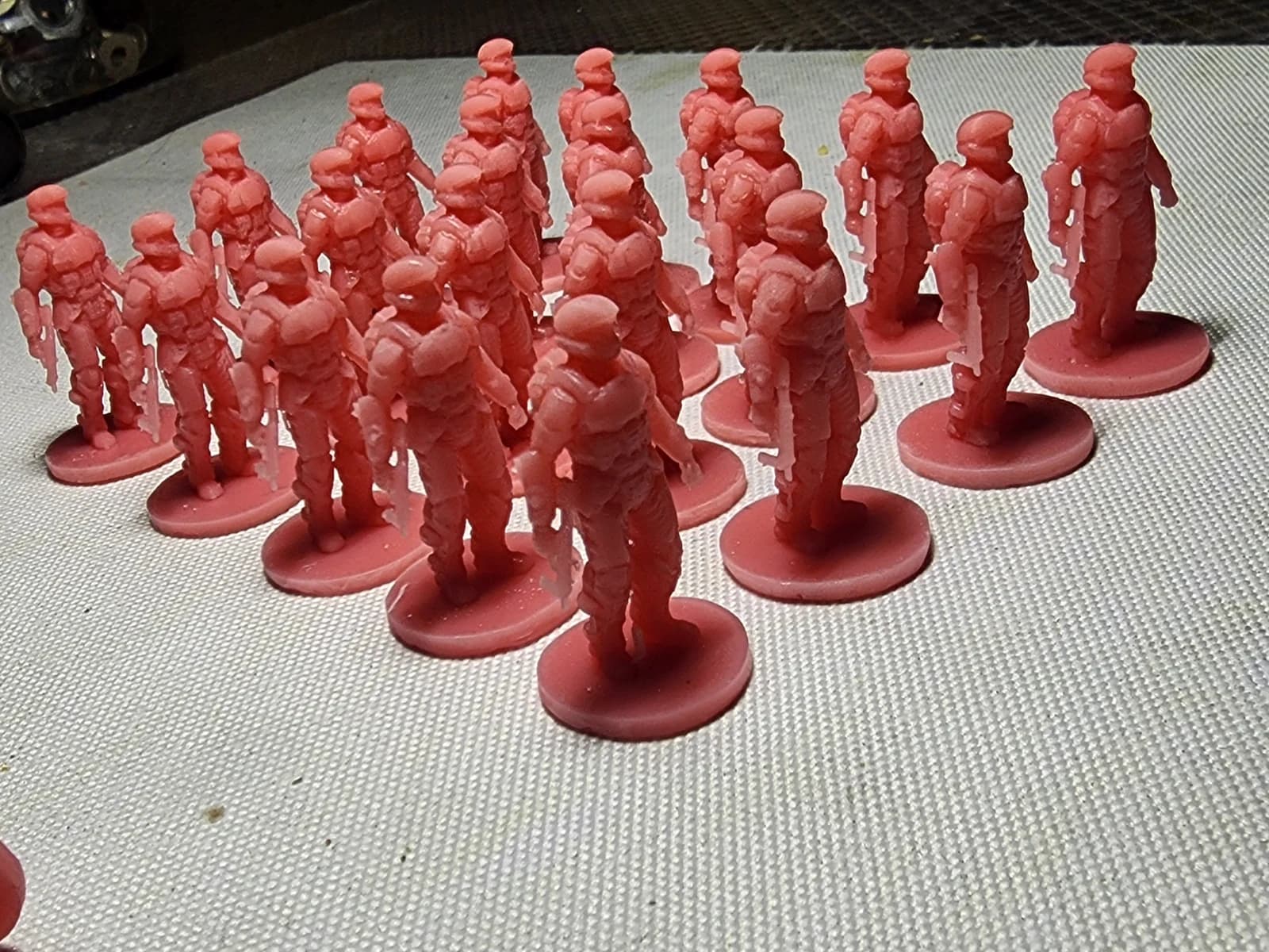 Rows of red soldier miniatures with helmets and equipment on round bases.