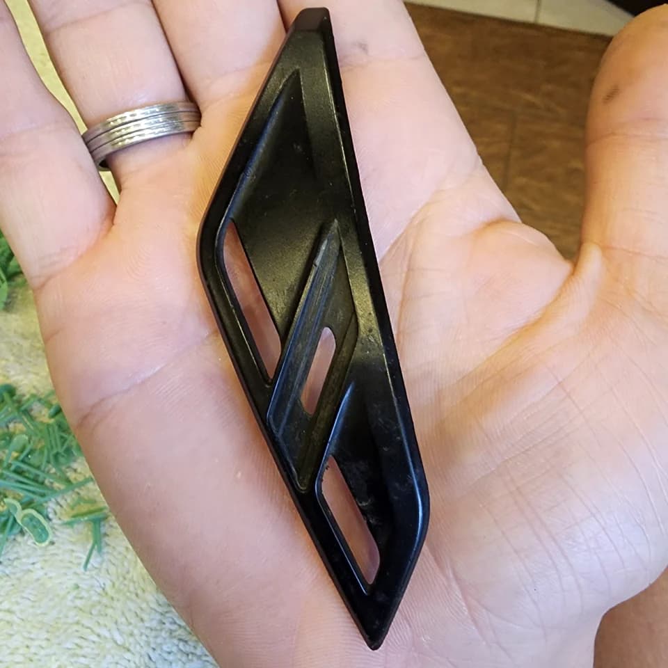 An elongated black trim piece with three slots resting on a palm.