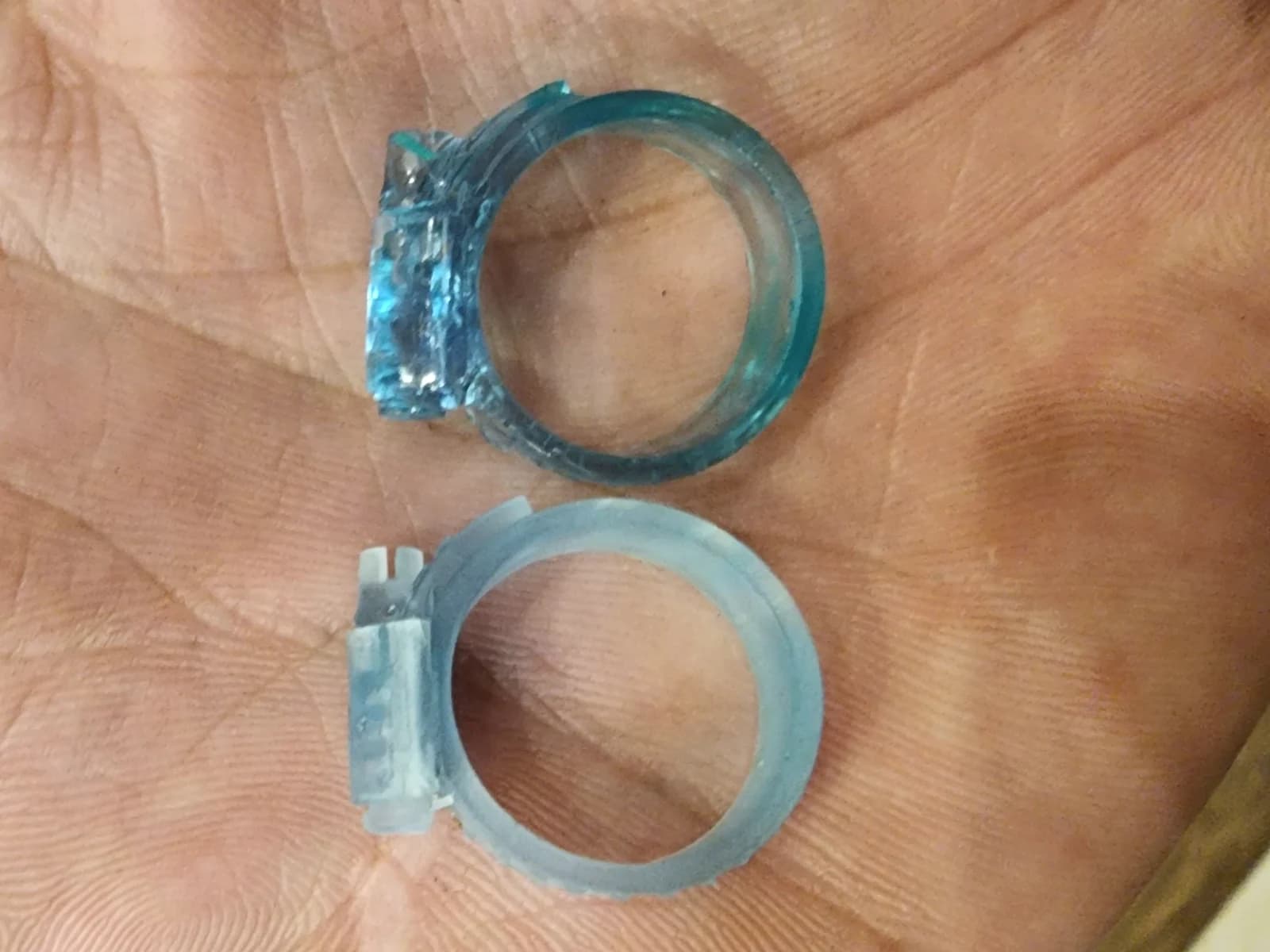 Pale and blue translucent mounting rings with side tabs resting on a palm.