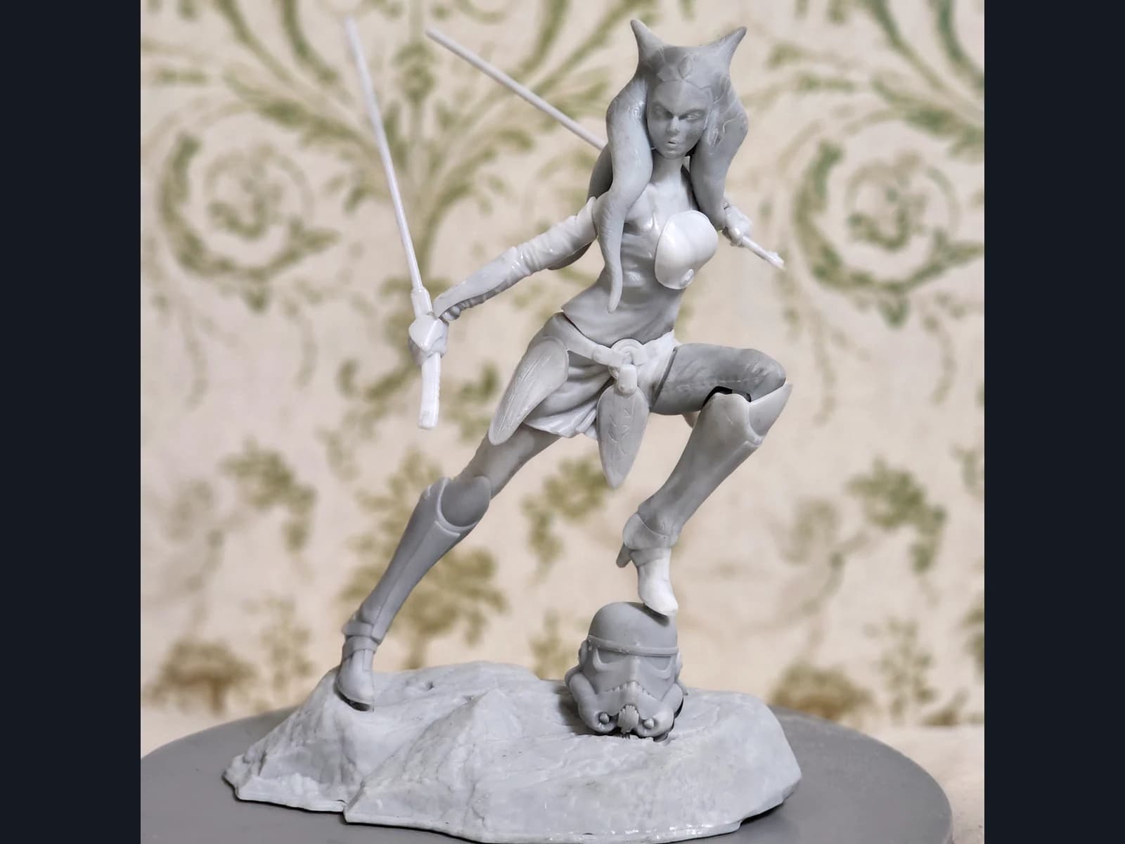 Grey Ahsoka figurine with two swords on a textured base.