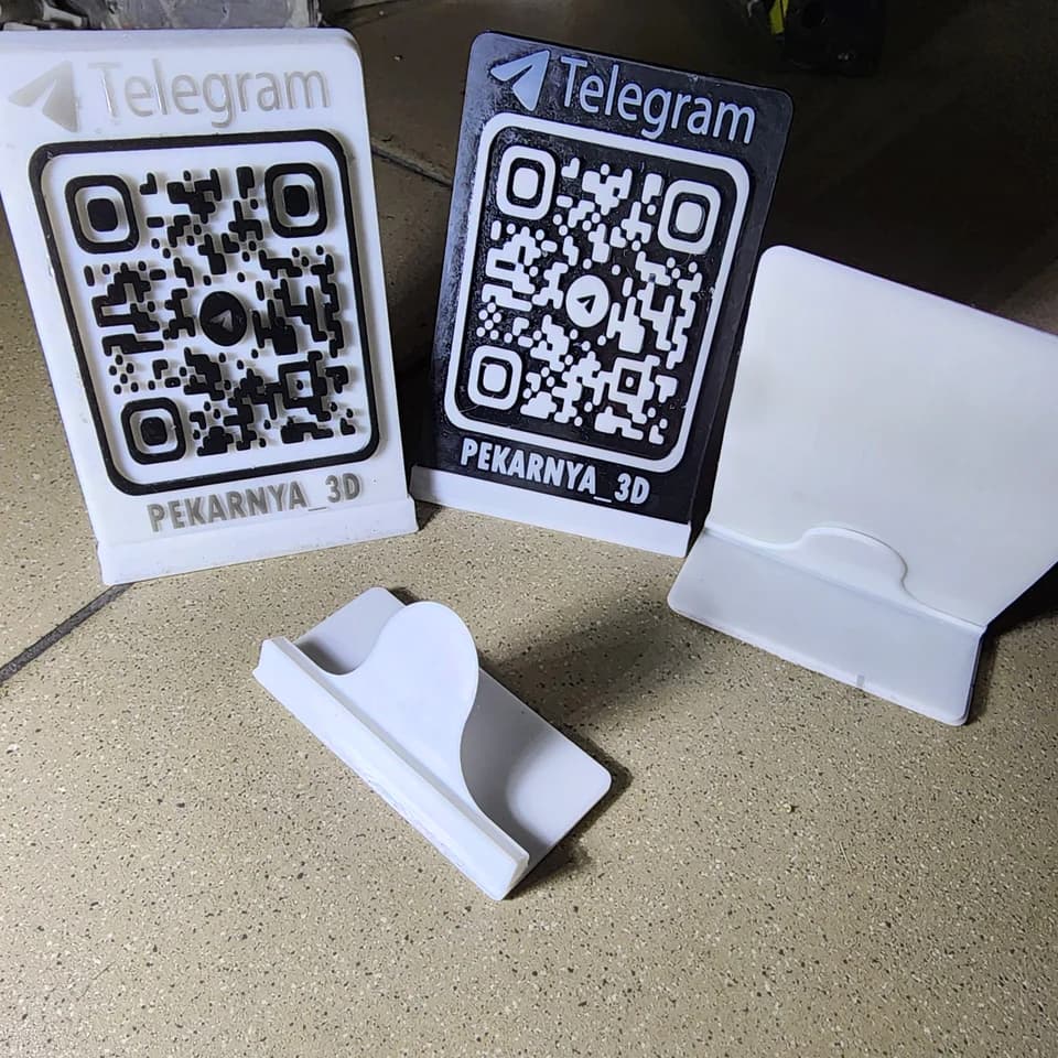 Light and dark QR signs with Telegram lettering, a white panel and a separate stand on a work surface.