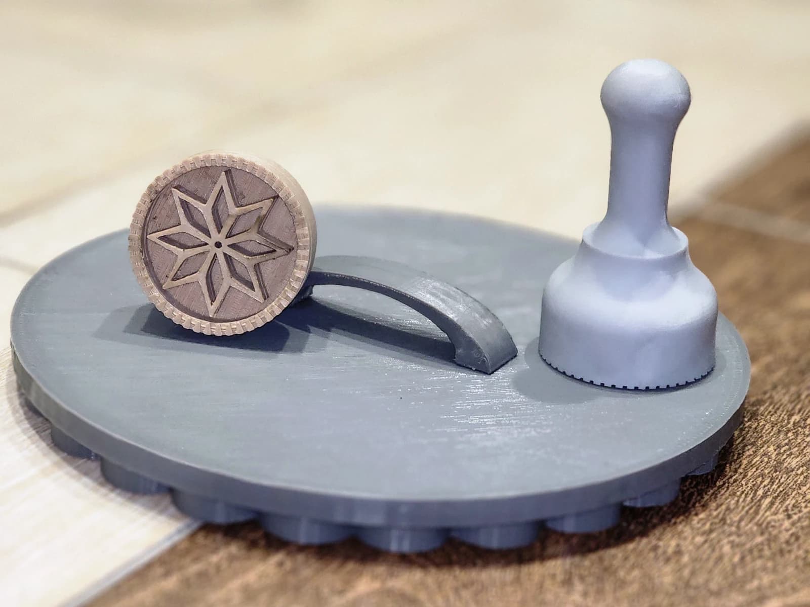 A round stamp with an eight-point geometric pattern and a grey handle on a circular stand.