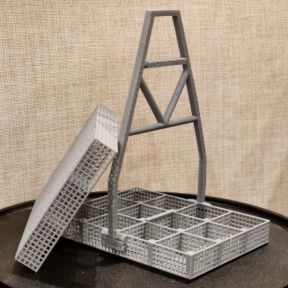 A grey mesh basket with dividers and a tall handle, with a separate mesh section standing beside it.