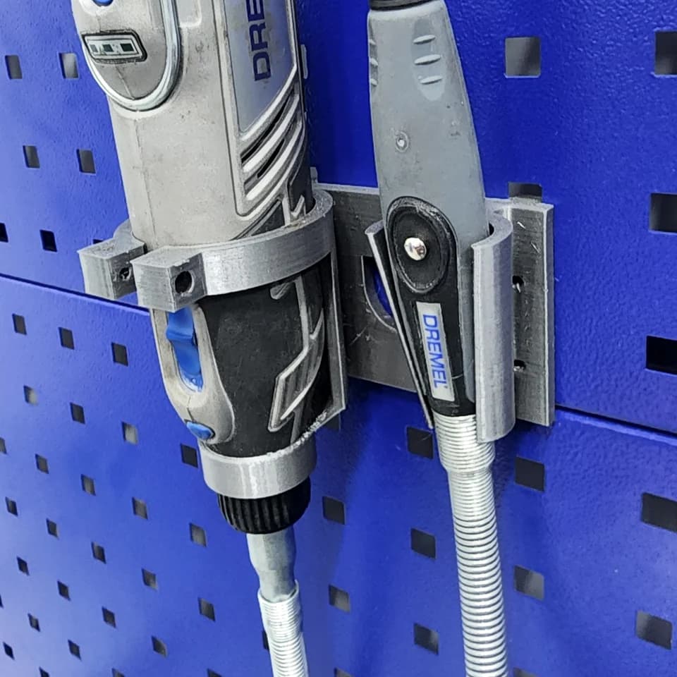 Grey holders for a rotary tool and flexible-shaft handpiece mounted on a blue perforated panel.