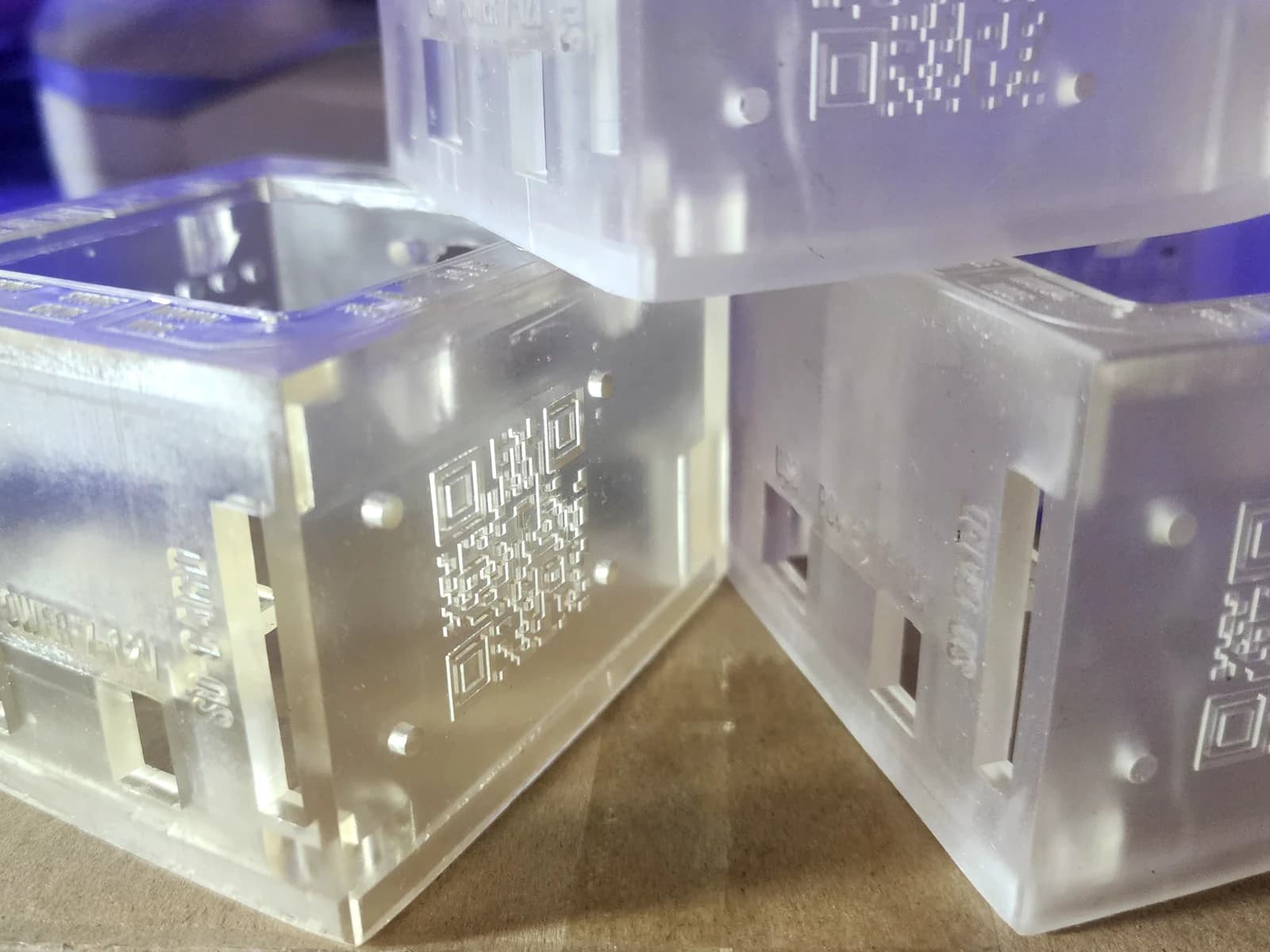 Close-up of translucent enclosure parts with holes, slots and raised QR codes.